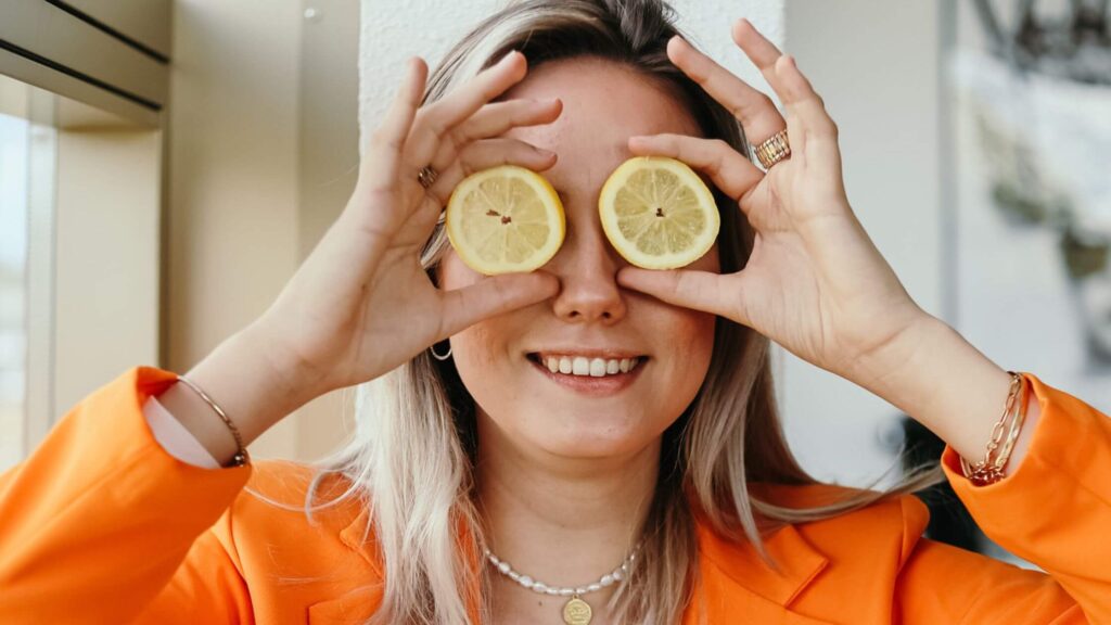 vrouw met oranje pak en gele citroenen voor ogen