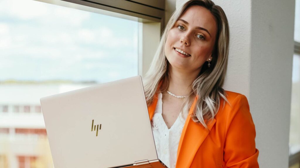 lachende vrouw in camera met laptop in hand